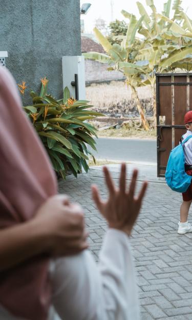 boy waves goodbye to his parents on his way to school