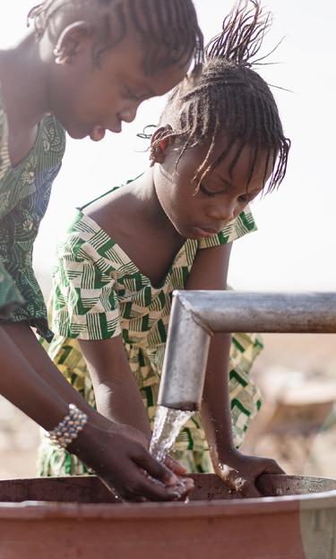 Girls collecting groundwater from a pump