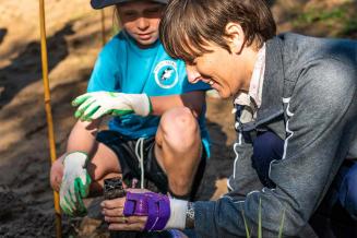  Picture of Grey Coupland and a girl, smiling and planting a tree seedling 