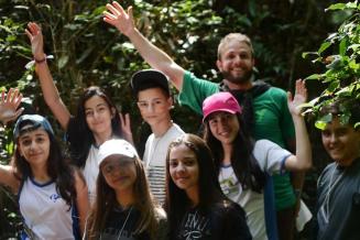 Photo d'un groupe d'étudiants debout dans la forêt tropicale, saluant et souriant