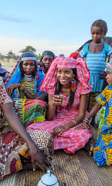 Hindou Oumarou Ibrahim in center of women and children drinking tea