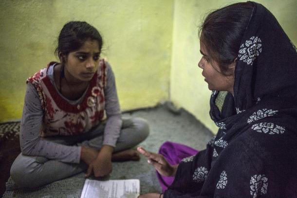Two women sitting on carpet, learning to read