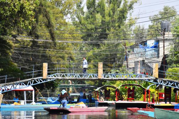 Habitantes de un barrio de Xochimilco entre trajineras y puentes sobre canales de agua de la zona.