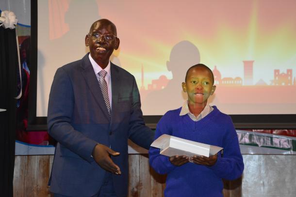 Dr. Belio Kipsang awards a prize to a learner.