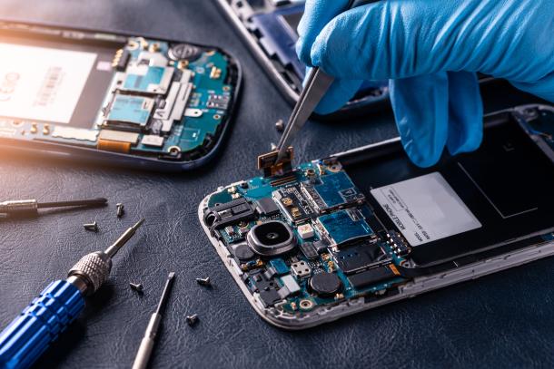 Zoomed photo of someone inserting an electric component into a smartphone