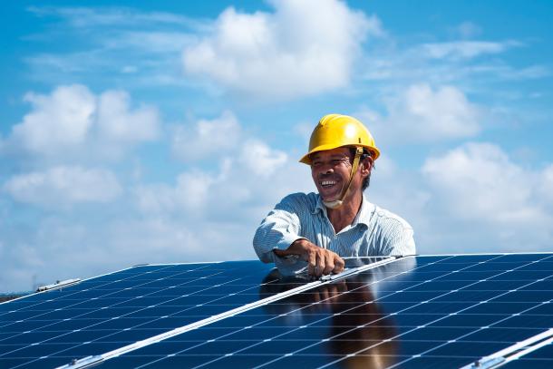 A smiling worker installs solar panels
