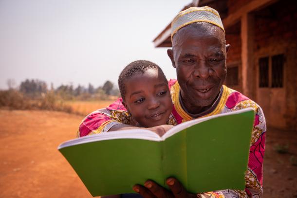 african grandfather reads a book with granddaughter