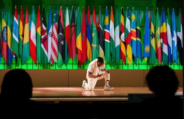 A man kneeling in front of flags